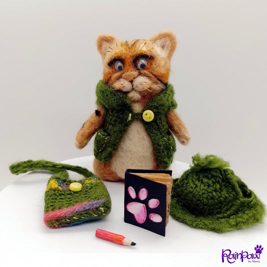 Cat-shaped plush toy with green hat, small bag, and book on a white background