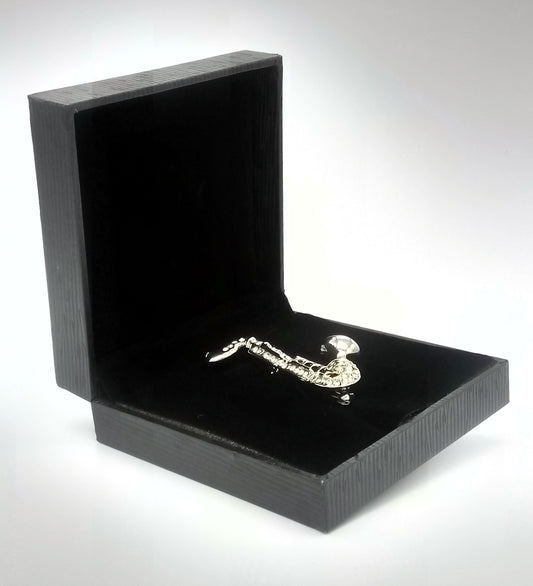 Silver saxophone keychain in an open black box on a white background