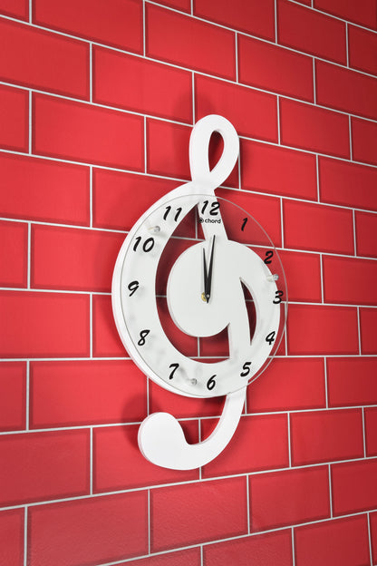 White wall clock shaped like a musical treble clef on a red brick wall