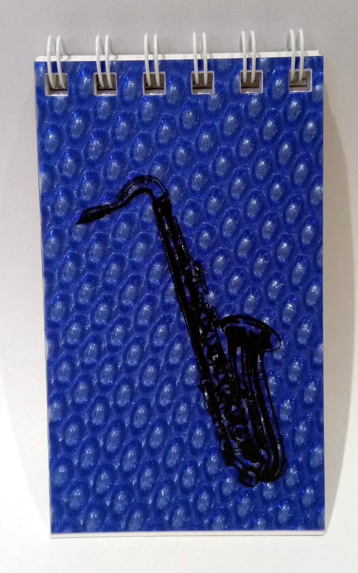 Notebook with a blue cover featuring a black saxophone design on a white background