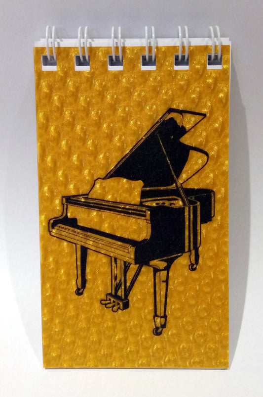 Notebook with a grand piano illustration on a gold background