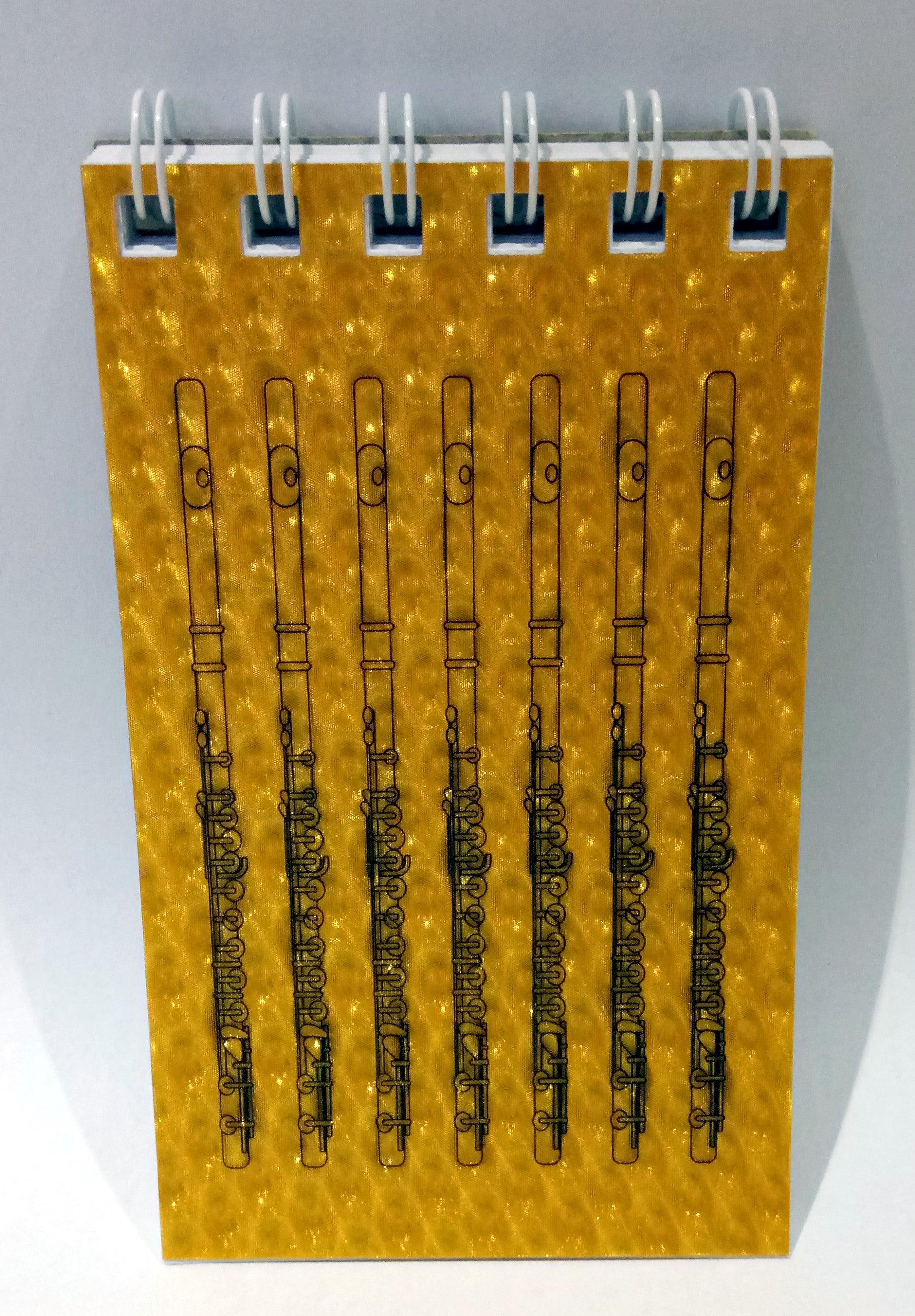 Notebook with flute designs on a yellow cover against a grey background