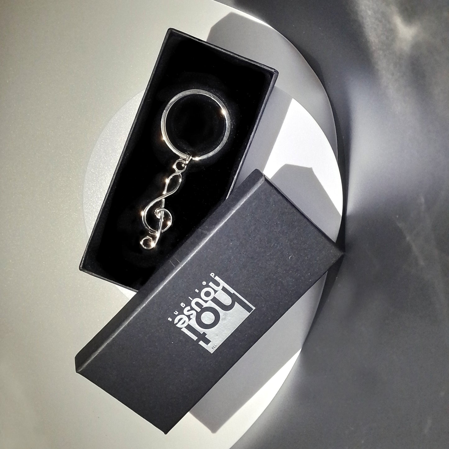 Keychain in a black box with 'hot house' branding on a reflective surface.