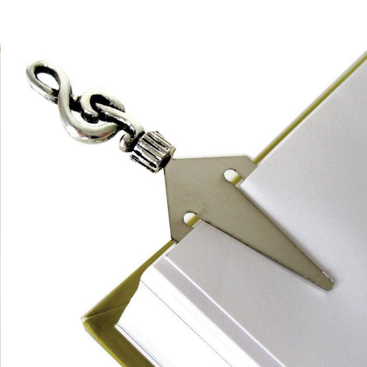 Close-up of a silver bookmark shaped like a treble clef on a white page.