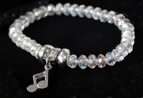 Bracelet with clear beads and a silver music note charm on a dark background
