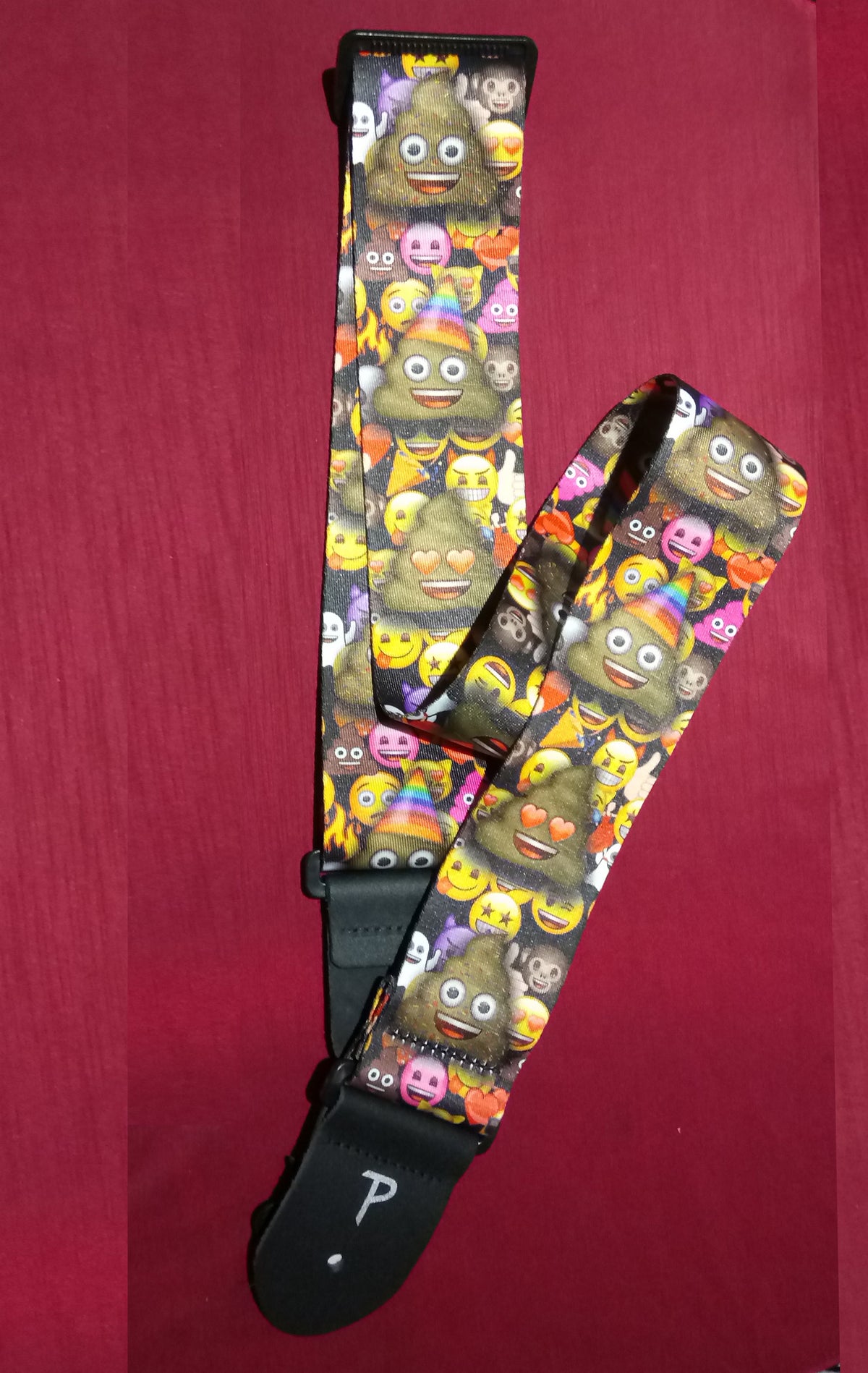 Multicolored emoji-patterned guitar strap on a red background
