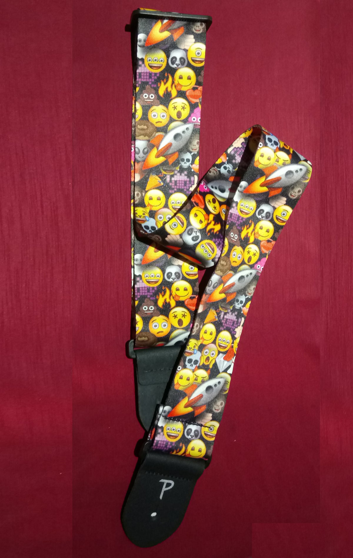 Guitar strap with emoji pattern on a red background
