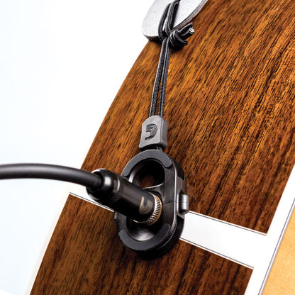 Close-up of a guitar with the device which one would need if the strap button serves as jack input and the strap won't stretch to it or for commodity