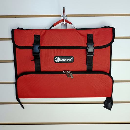 A red and black Attitude brand utility pouch or document bag hanging from a metal hook on a white slatwall. The bag features a top flap with two black plastic buckle straps, a central zippered pocket, and a bottom zippered compartment.