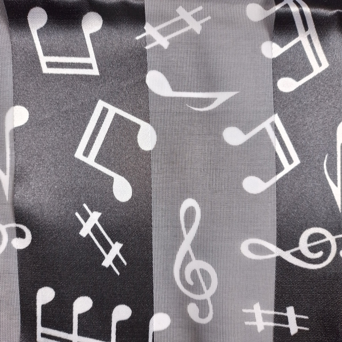 A close-up of a fabric or mesh black material with a repeating white music notes.