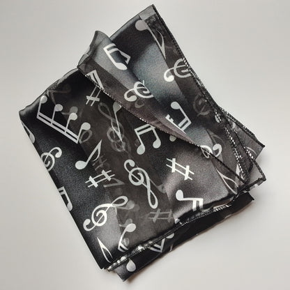 A black sheer scarf with a white music note and staff pattern, folded on a white background.
