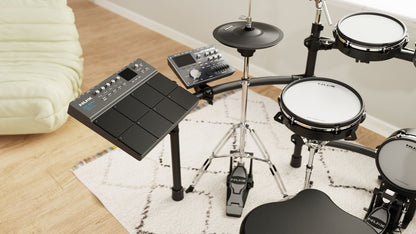 Electronic drum set on a rug with a beige couch in the background