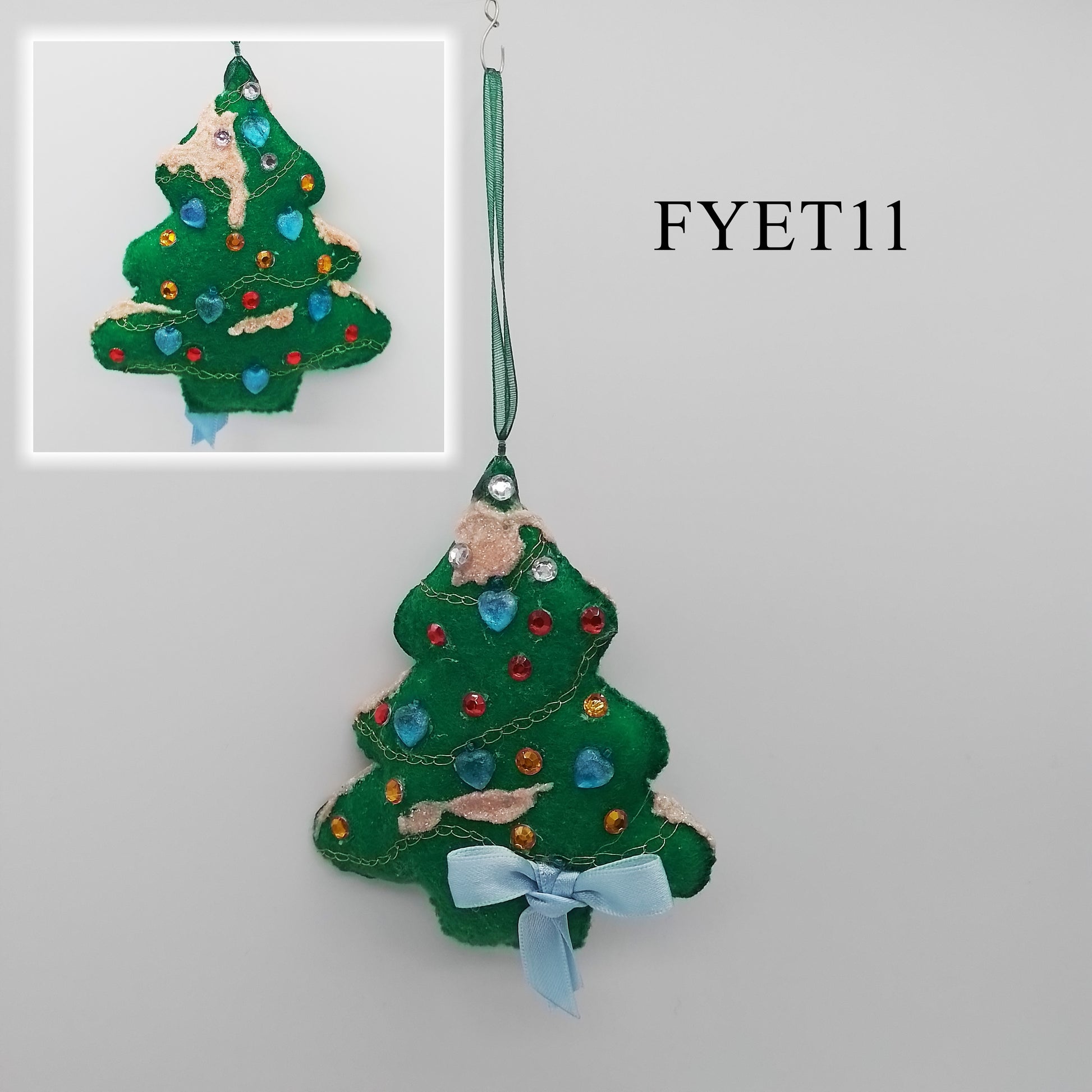 A fun and unique felt green Christmas tree ornament, decorated with colourful rhinestones and a light blue bow, is perfect for adding some personality to your holiday décor. A green, thin ribbon is attached to one end to form the hanger.