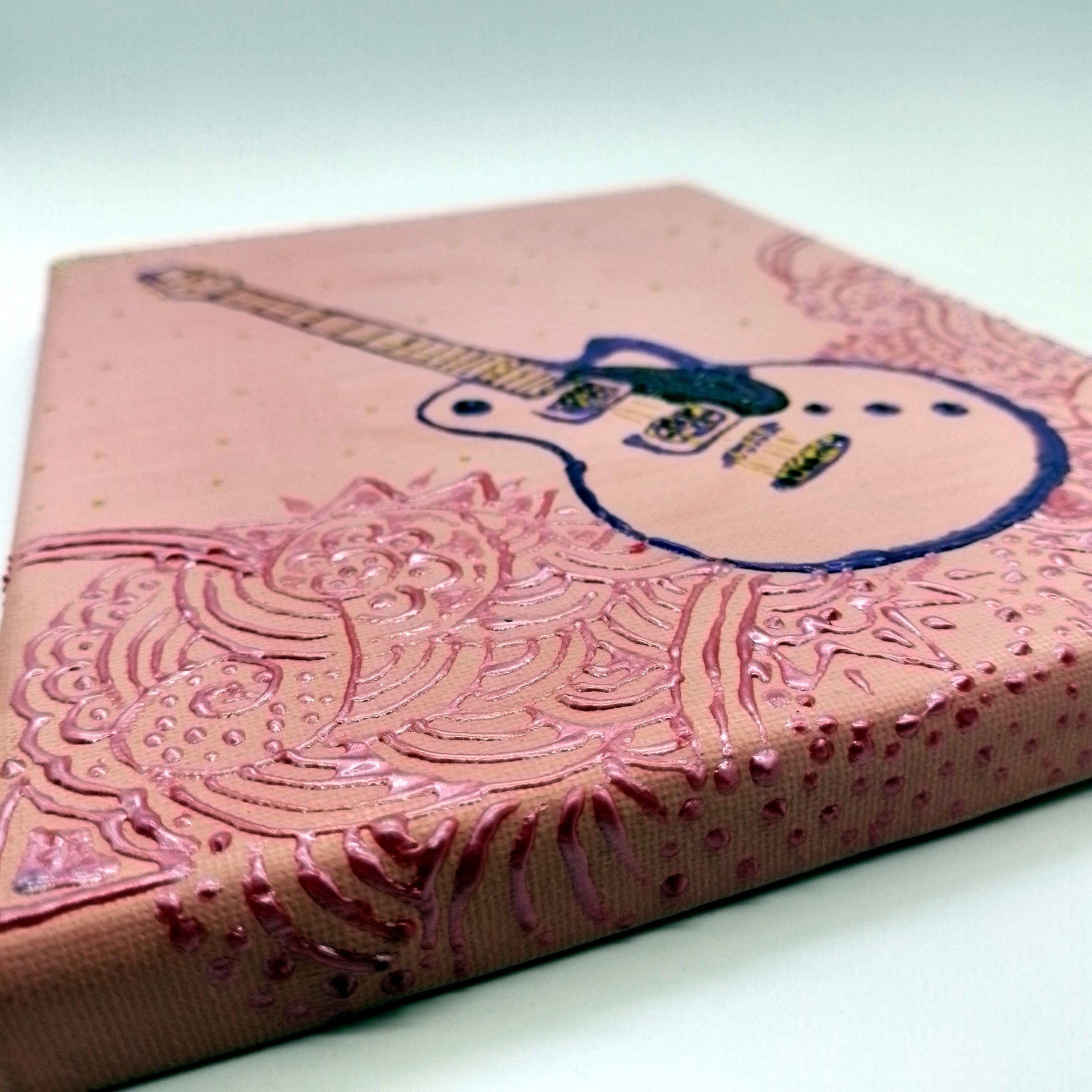 Detail of the painting with purple, black and gold electric guitar and pink decorative elements on light pink  background. The shape of the instrument is a light relief on a flat surface.