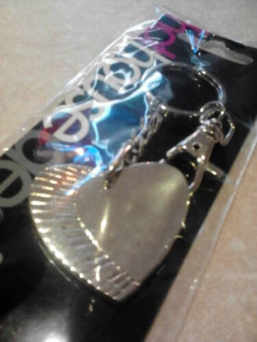 Heart-shaped silver pendant on a clear card with visible brand name.