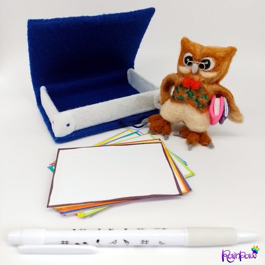 A beautifully crafted, handmade desk set featuring a felted owl pen holder and a blue felt-covered box resembling a book, containing blank paper for notes.