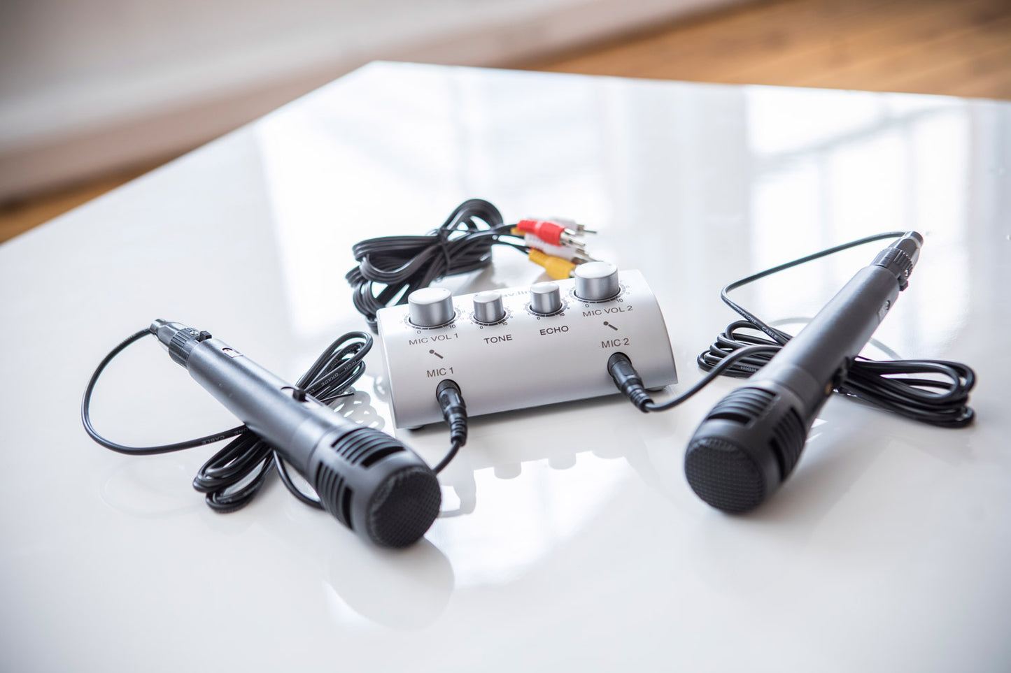 Two microphones and a audio/video switch box on a white surface.