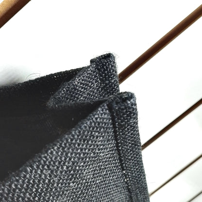 Close-up of a dark charcoal grey woven fabric, showing the texture and folded edges against a bright white background.