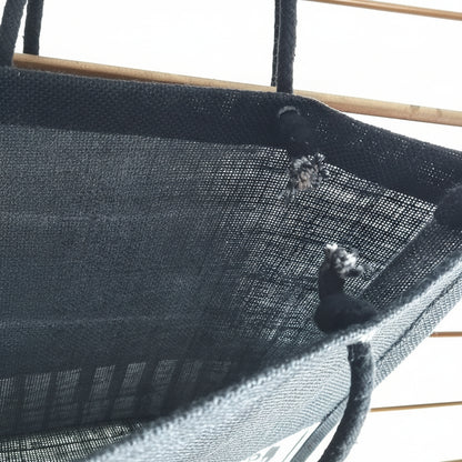 Close-up of a black mesh fabric shopping bag with thick charcoal grey rope ties, shown against a bright white background.