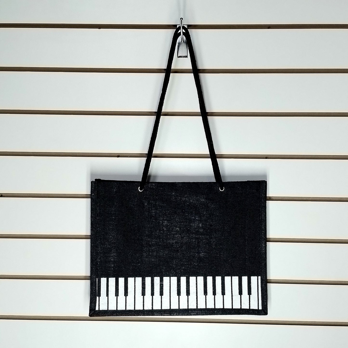 A black Music Themed Reusable Shopping Bag, displayed on a white slatted wall.
