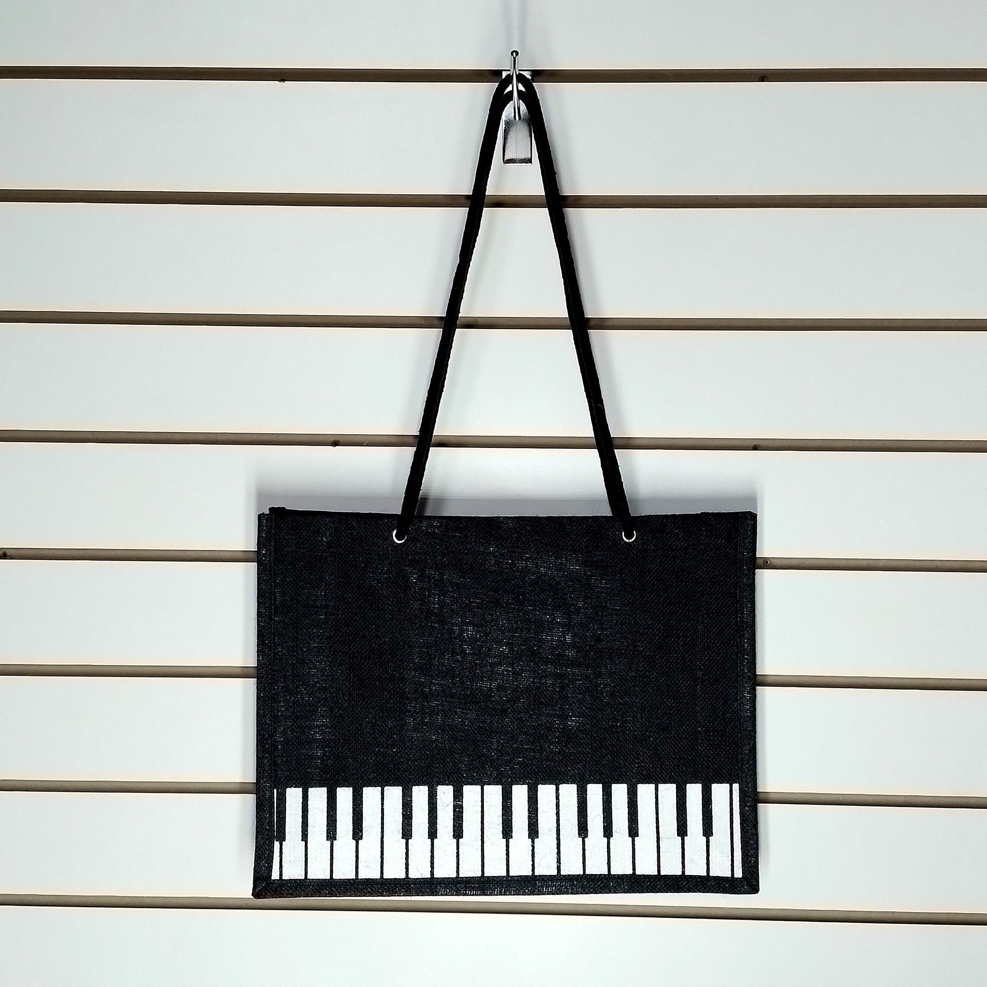 A black Music Themed Reusable Shopping Bag, displayed on a white slatted wall.