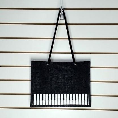A black Music Themed Reusable Shopping Bag, displayed on a white slatted wall.