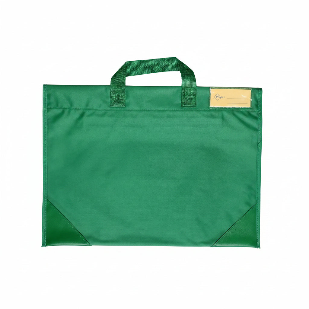 A green fabric school bag with single top handle and a clear plastic label pocket the upper corner. Photographed, laid flat on a white surface.