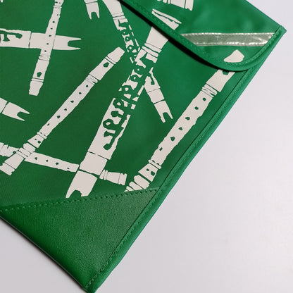 A close-up of a green envelope-style pouch or clutch with a white bamboo graphic print and a reflective silver strip on the flap, photographed on a light gray background.