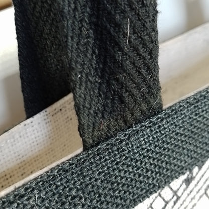 Close-up of a black woven fabric strap or handle attached to a white mesh bag, showing the texture of the material.