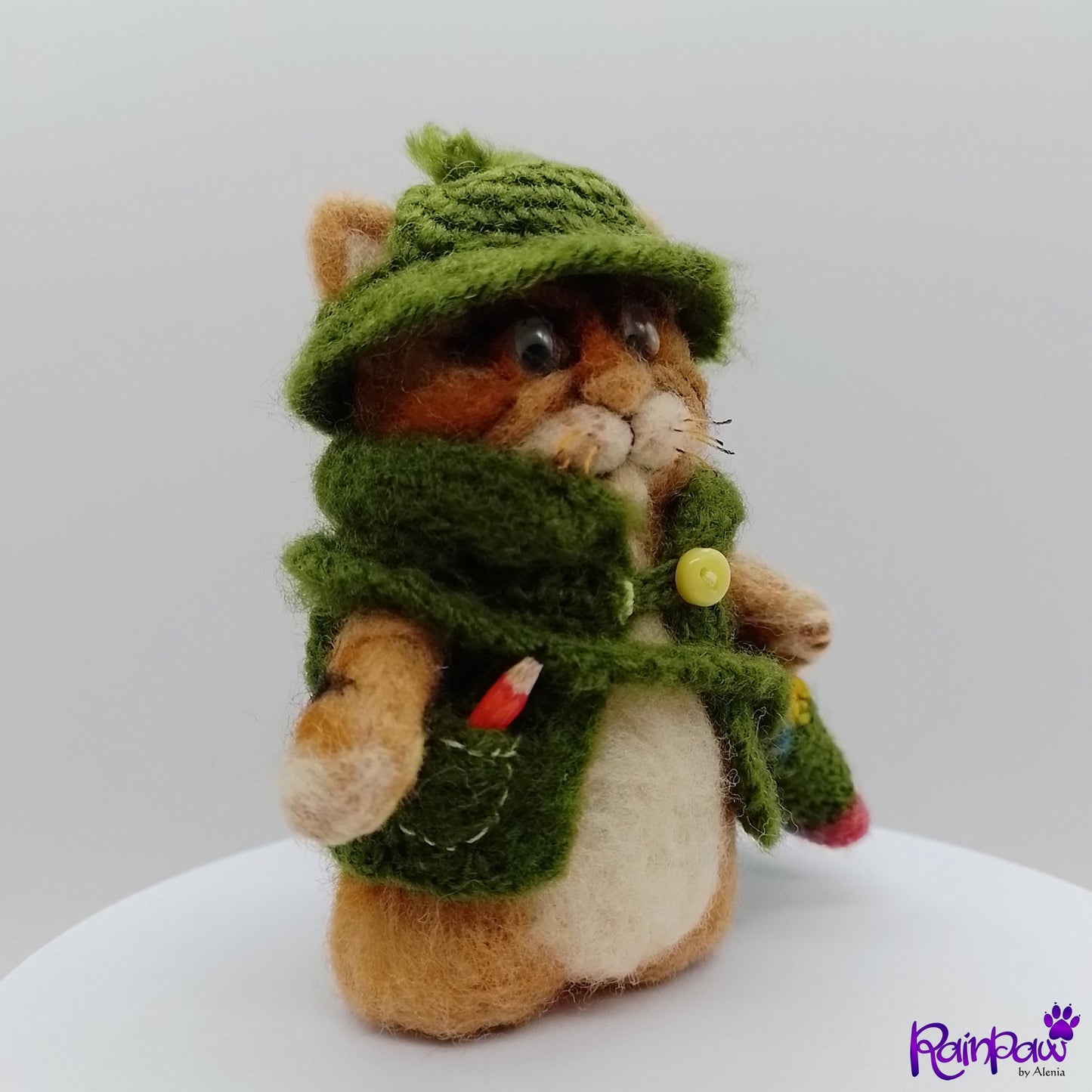 Stuffed animal resembling a cat or a tiger wearing a green hat and a messenger bag on a white background