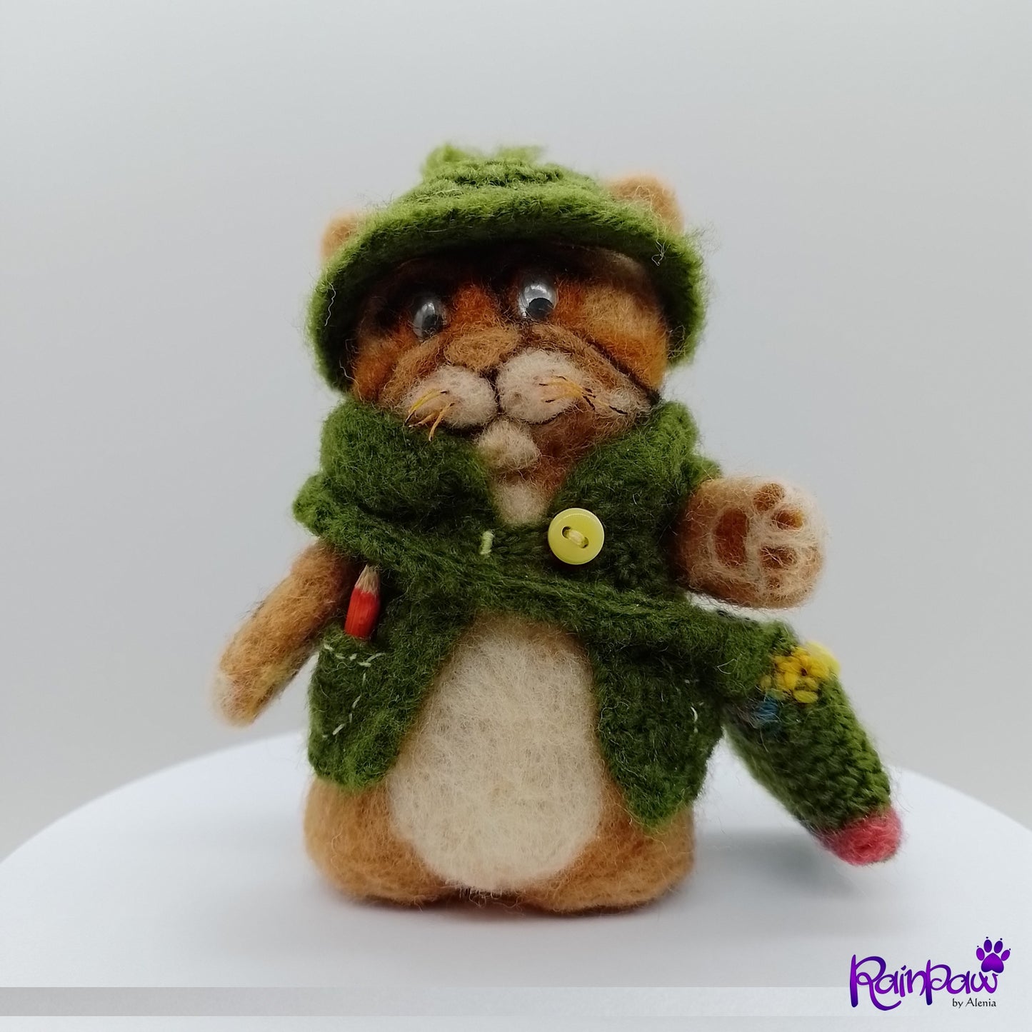 Stuffed ginger cat/tiger resembling a cat in a green coat with a hood on a white background