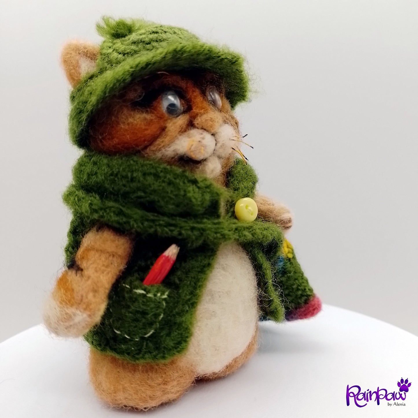 Stuffed ginger cat/tiger wearing a green hood and messenger bag with a white background