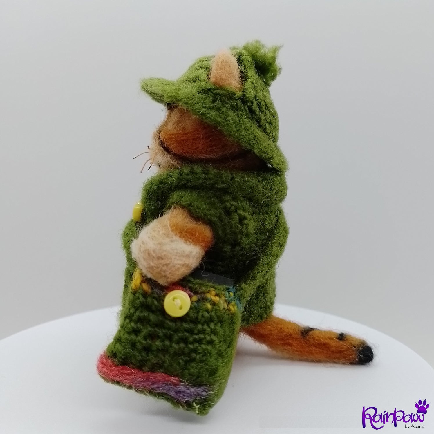 Small stuffed ginger cat/tiger  wearing a green outfit with a hood on a white background