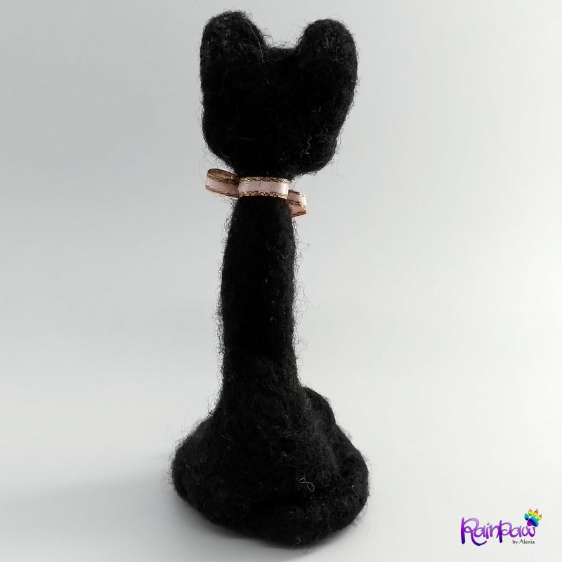 Back view of a black cat with a pink bow on a white background