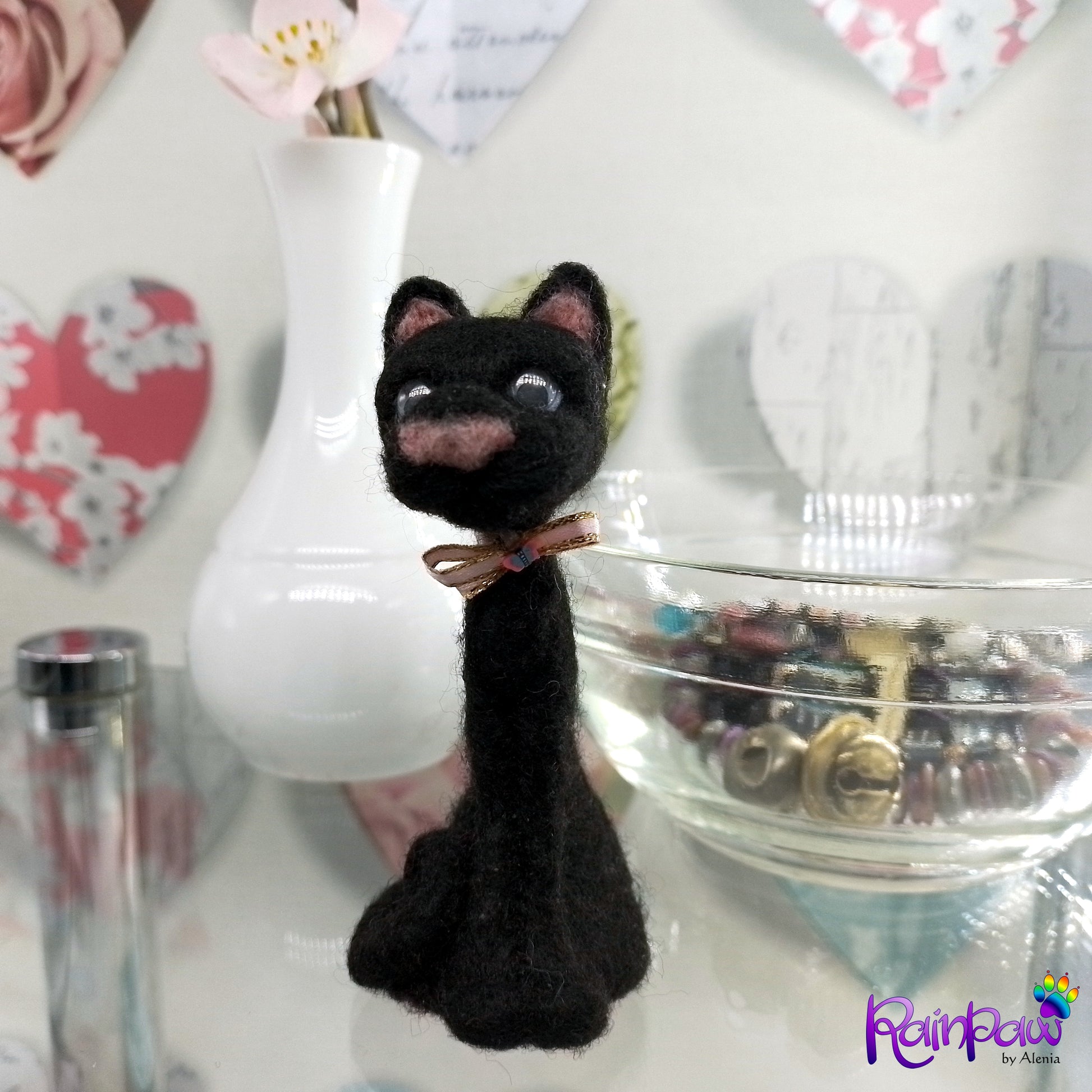 Black cat figurine with a bow tie on a surface with decorative items in the background