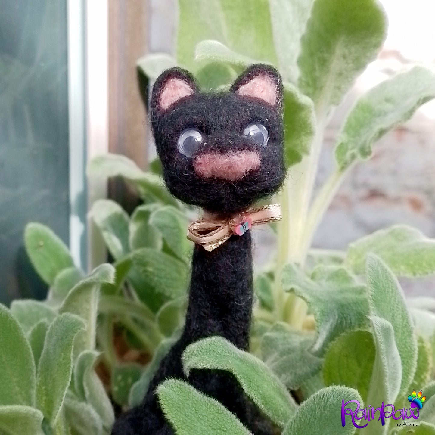 Black cat with a pink bow in a green plant