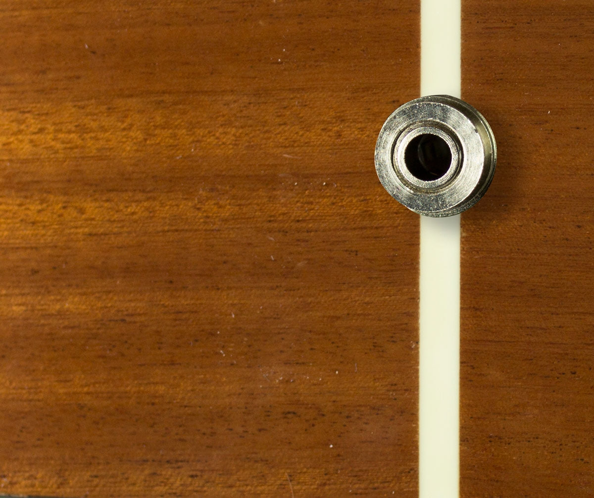 Close-up of a wooden guitar body with a jack output coming out of it.