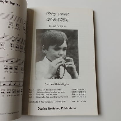An open printed sheet music book or instruction booklet on a white background, showing the title 'Play Your Ocarina', a black-and-white portrait photo, and musical notation pages partially visible.
