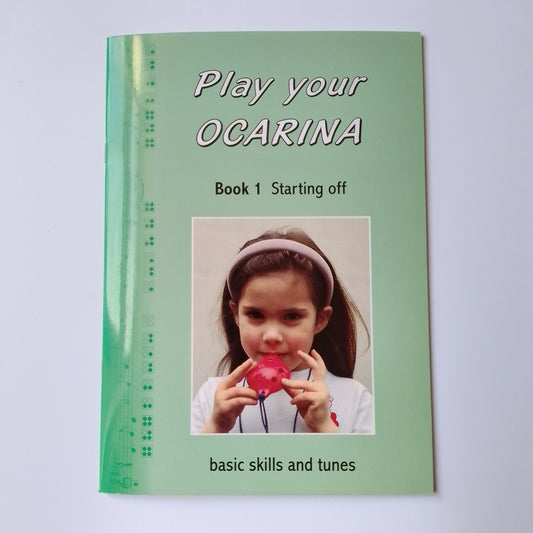 A green children's music book titled 'Play your OCARINA Book 1 Starting off' with a photo of a young girl playing a red ocarina. Photographed on a white background.