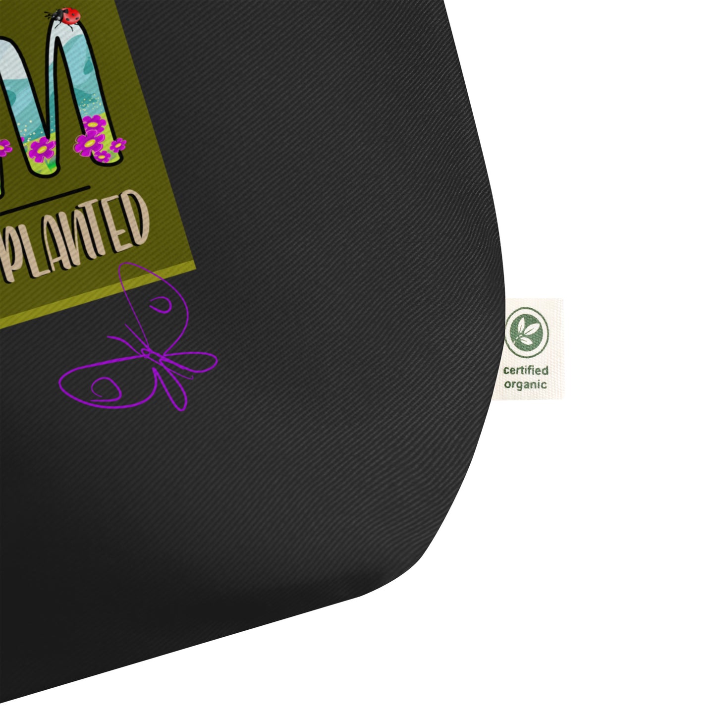 Black bag detail with a purple butterfly design and a green label with text and a logo on a white background