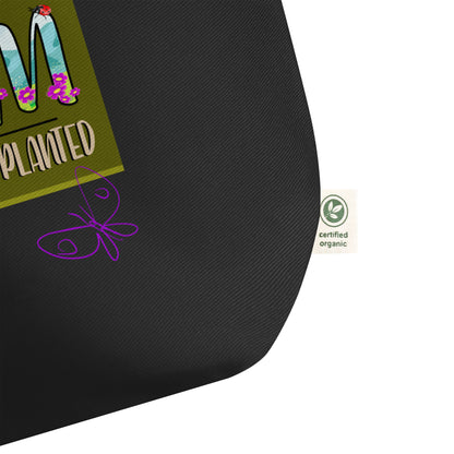Black bag detail with a purple butterfly design and a green label with text and a logo on a white background