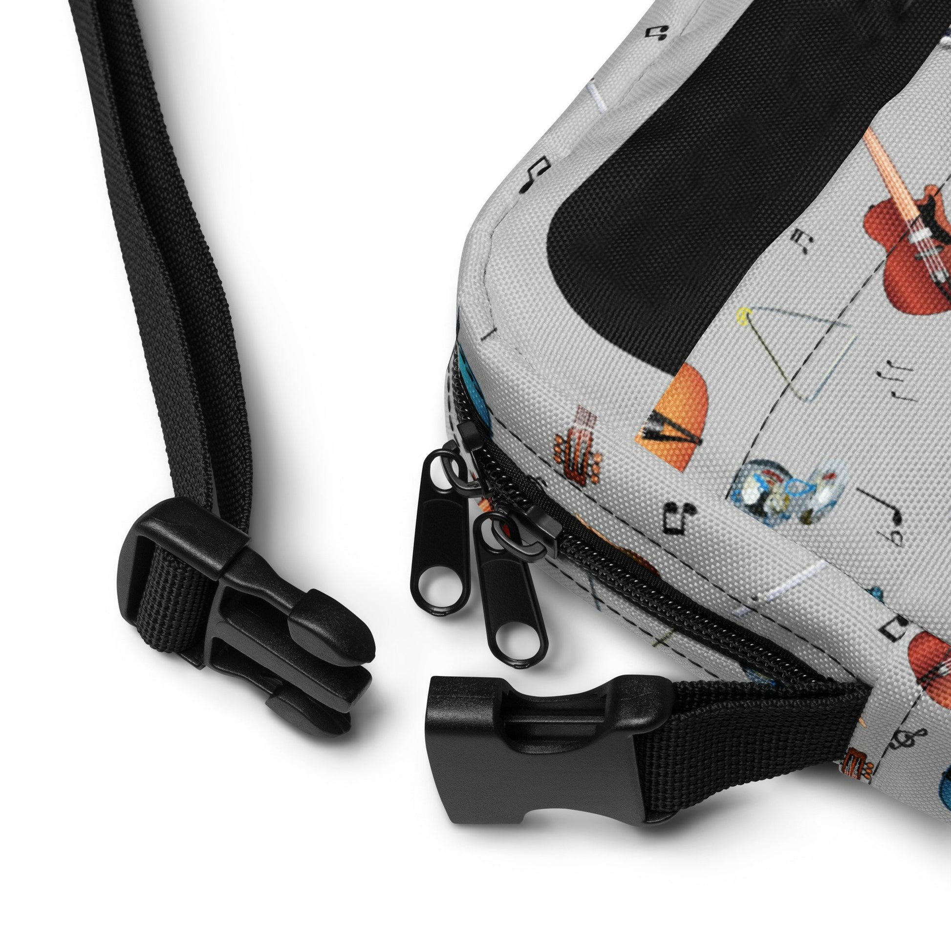 Grey crossbody bag with black adjustable shoulder strap (with black plastic clip), inside and outside pockets, sturdy fabric, and two-way zipper. The design features a repeat pattern of colourful musical instruments and black musical notes on a grey background.
