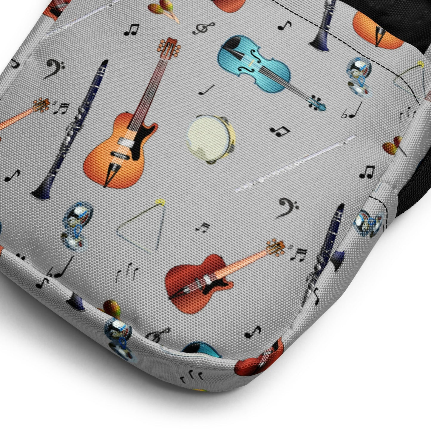 Grey crossbody bag with black adjustable shoulder strap (with black plastic clip), inside and outside pockets, sturdy fabric, and two-way zipper. The design features a repeat pattern of colourful musical instruments and black musical notes on a grey background.