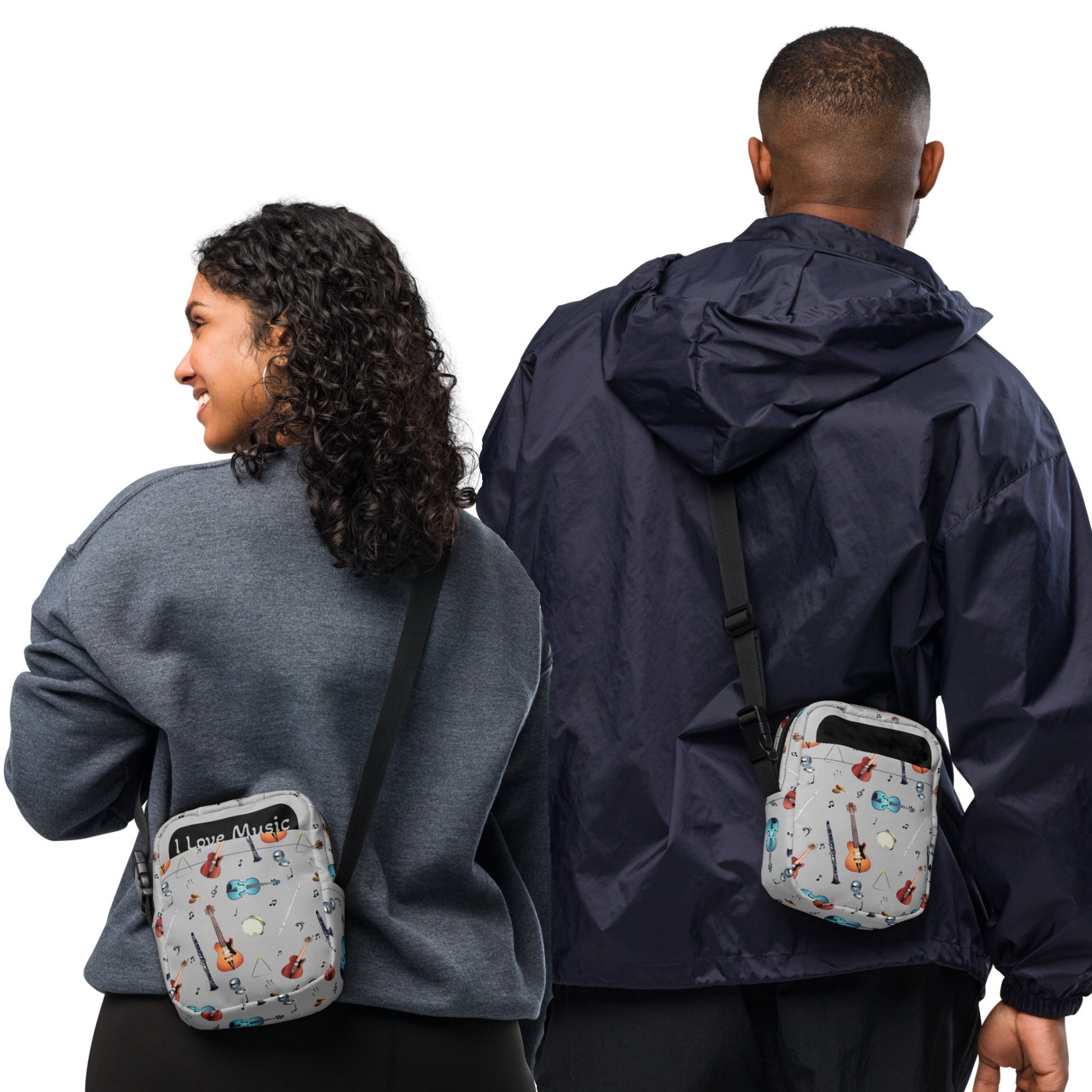 Grey crossbody bag with black adjustable shoulder strap (with black plastic clip), inside and outside pockets, sturdy fabric, and two-way zipper. The design features a repeat pattern of colourful musical instruments and black musical notes on a grey background.