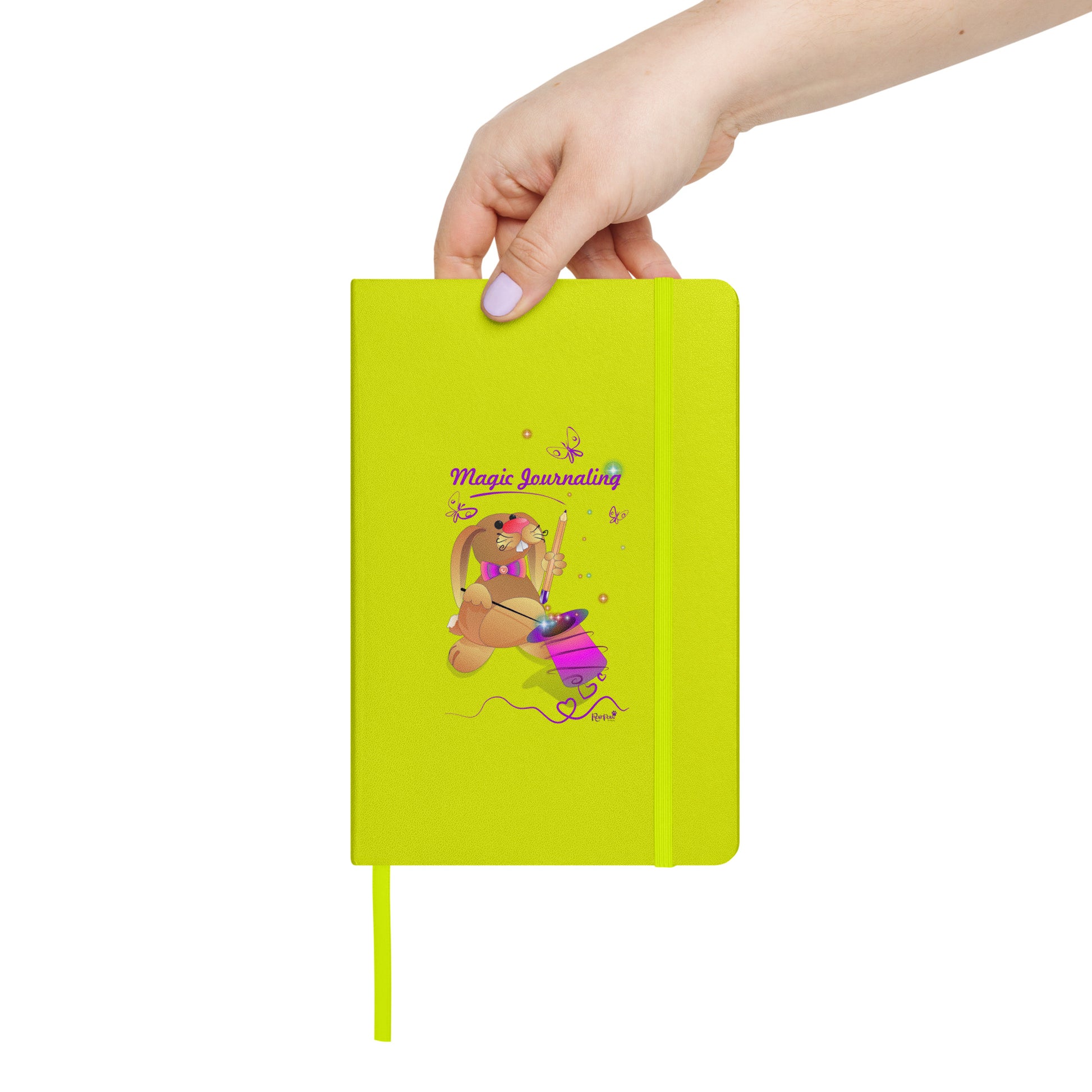 Lime-green notebook held by a hand on a white background. - The cover features a bunny holding a magic wand and a pencil pulled from its top hat, surrounded by butterflies, colourful stars, and hearts, giving the journal an enchanting feel. The words "Magic Journaling" are written on the cover.