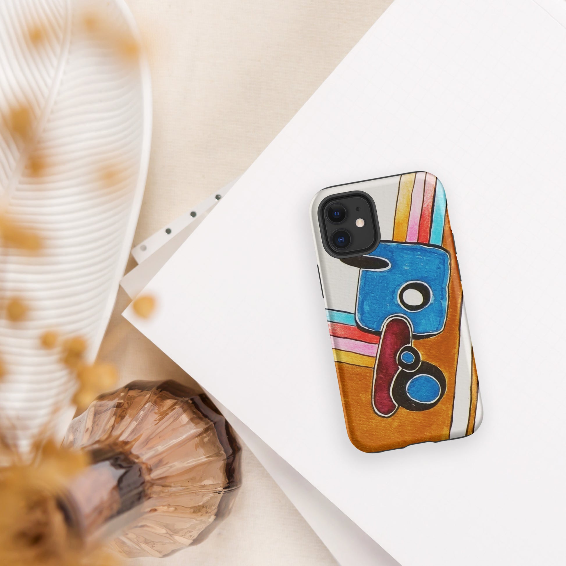 Phone case with colourful abstract design on a white surface with decorative elements