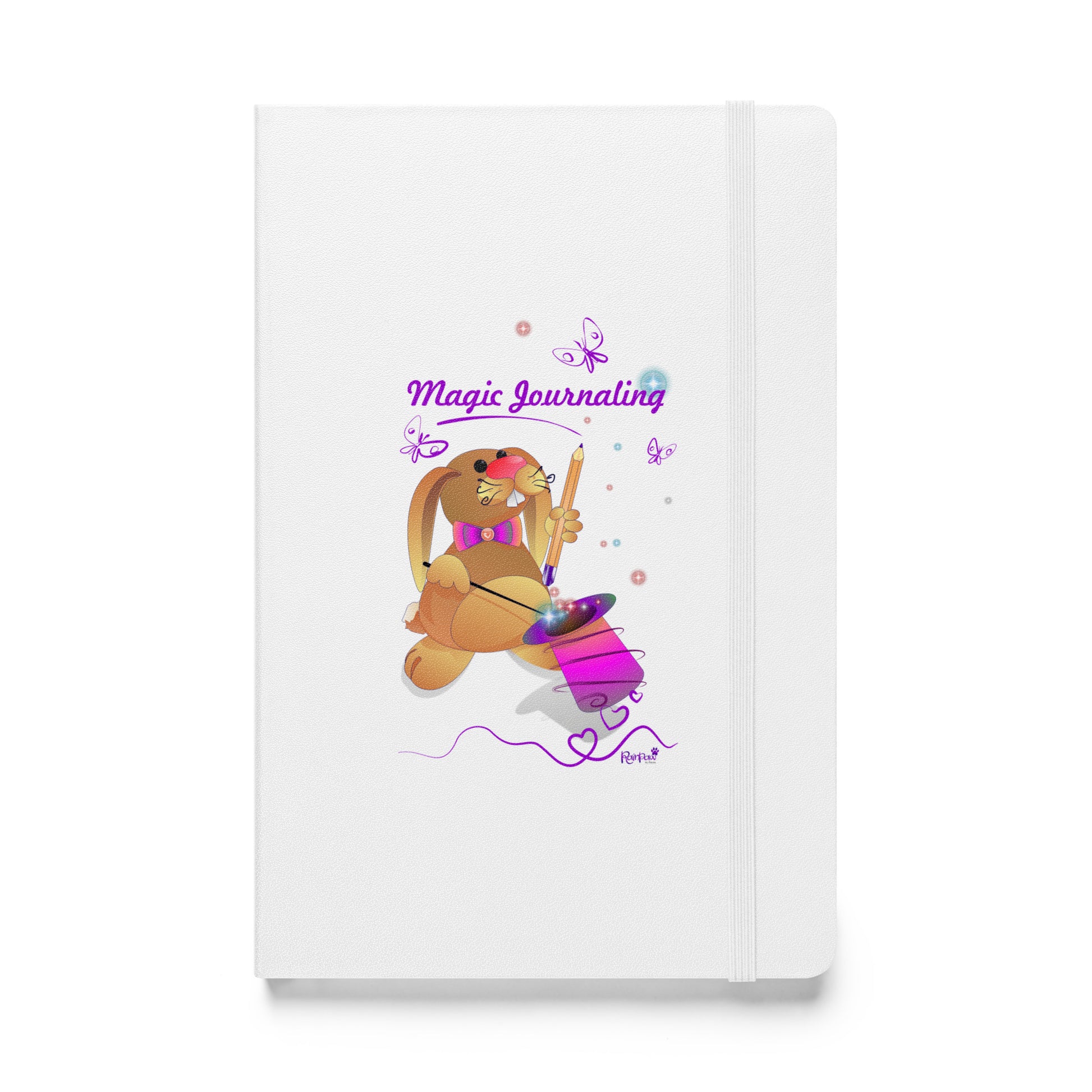 White notebook on a white background. A rubber band wraps around the opening edge of the journal to keep it closed. - A  journal with a rubber band. The cover features a bunny holding a magic wand and a pencil pulled from its top hat, surrounded by butterflies, colourful stars, and hearts, giving the journal an enchanting feel. The words "Magic Journaling" are written on the cover.