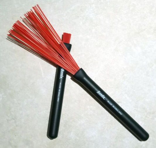 Two black brushes with red bristles on a textured white background