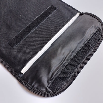 Close-up of a black fabric sleeve or pouch with a hook-and-loop closure and a white interior lining, shown on a light gray background.
