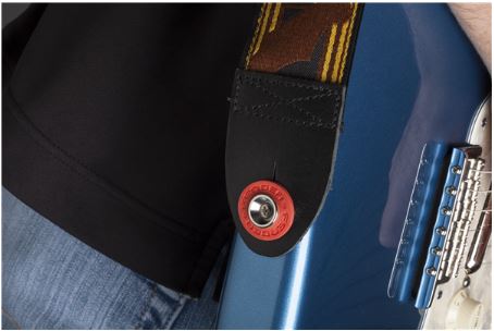 Close-up of a guitar strap with a red button on a blue electric guitar.